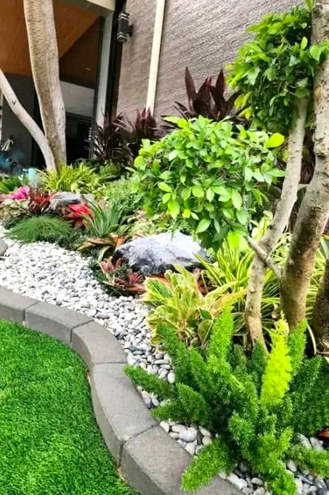 Curved stone border with river-rock planting beside a lawn